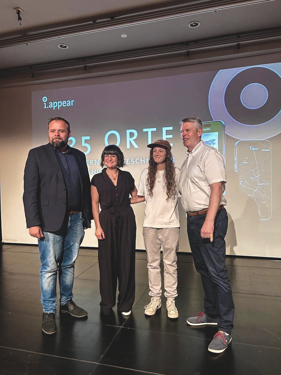 B&uuml;rgermeister Markus F&auml;&szlig;ler, Marilena Tumler, Maggy Haidacher und Werner Matt auf der B&uuml;hne im Kulturhaus Dornbirn vor der Projektion des Jubil&auml;umsrundgangs.