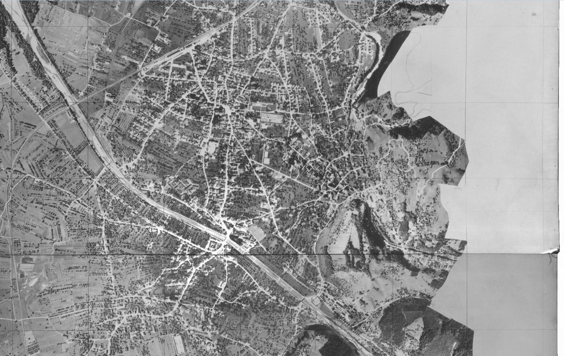 Historisches Schwarz-Weiss-Luftbild von Dornbirn mit dichter Bebauung, Strassennetz und Bahnlinie.